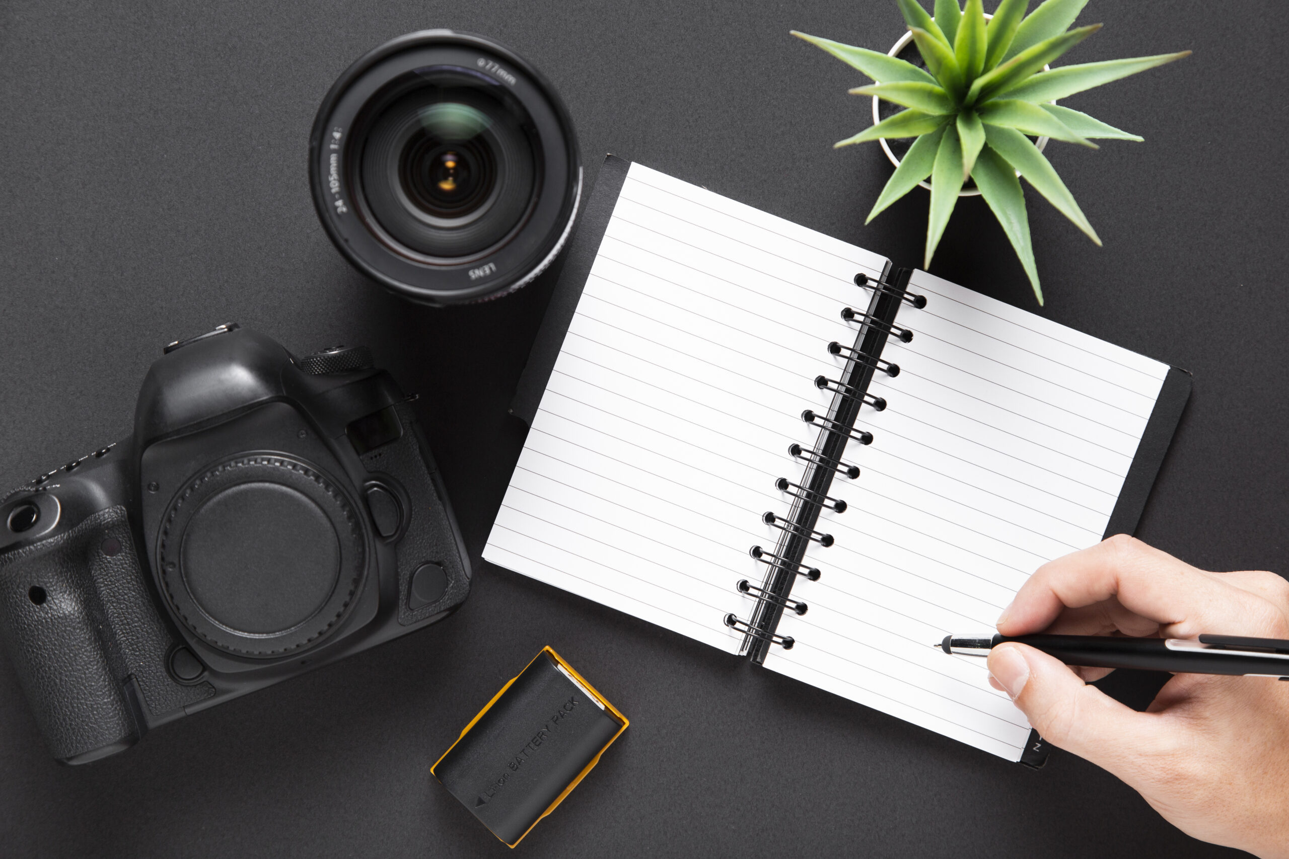 flat lay camera lenses notebook black background